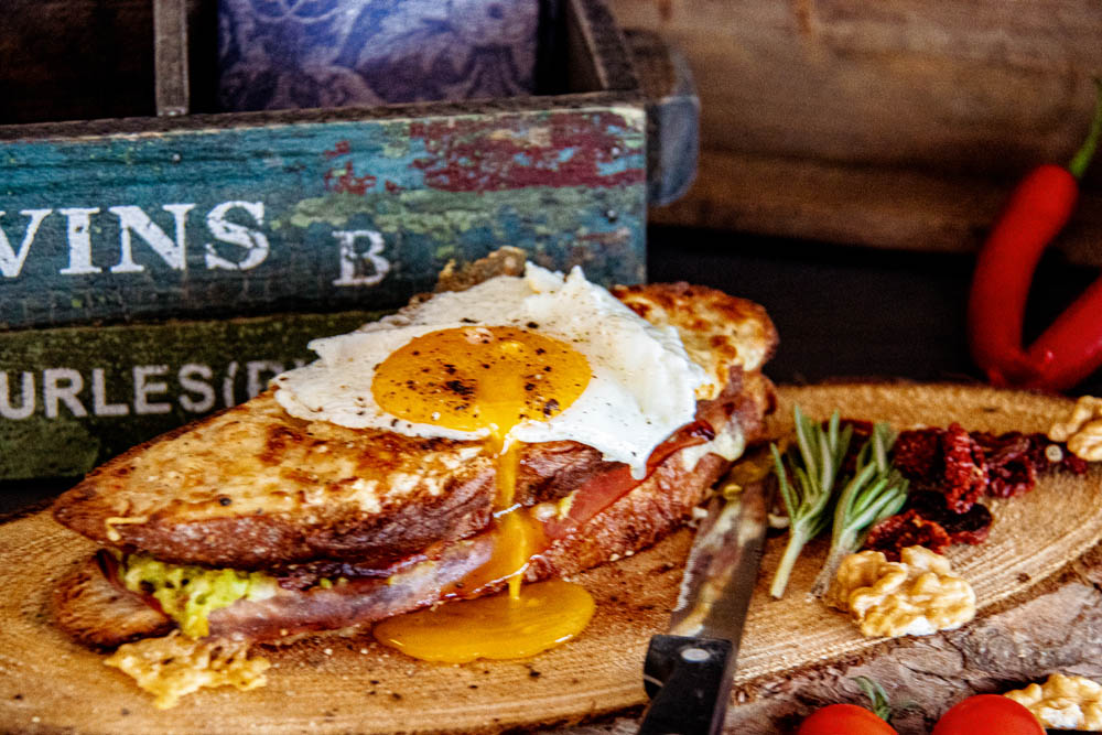 Croque Madame with a fried egg on top, served on a wooden plate